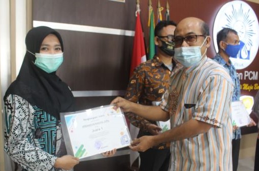 
 Ifrahatun Nadiya menerima penghargaan dari Ketua Majelis Dikdasmen PCM Gresik, Ahmad Subagiono. (Foto: Bening Satria)