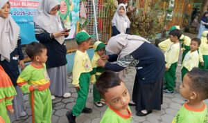 Penyematan name tag oleh kepala sekolah TK Aisyiyah 5 Bungah, Gresik. Senin, (14/7/2025) (Alkafiah/girimu.com)