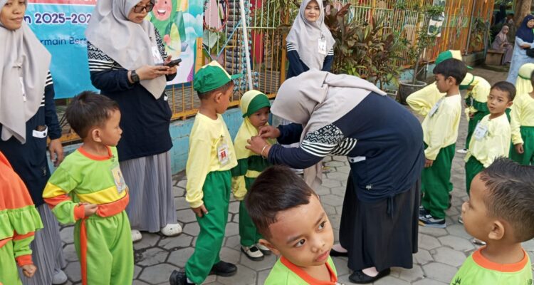 Penyematan name tag oleh kepala sekolah TK Aisyiyah 5 Bungah, Gresik. Senin, (14/7/2025) (Alkafiah/girimu.com)