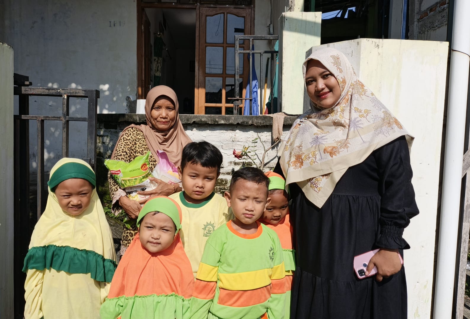 Ziyadatul Khoir Sumitro Sudjono (sebelah kiri) bersama dengan siswaTK dan KB Aiyiyyah 49 Griya kencana saat meyalurkan zakat fitrah ke warga sekitar sekolah. (Elisyah Susanty/GIRIMU.COM)