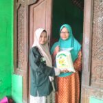 Winda, siswi SMK Muhammadiyah 2 Gresik, menyerahkan paket zakat fitrah kepada warga Desa Klampok dalam kegiatan penyaluran zakat oleh PR IPM SMK Muda Gresik. (Doc. Falaq)