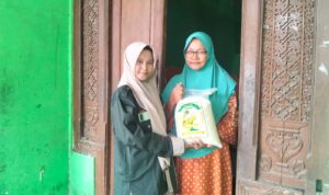 Winda, siswi SMK Muhammadiyah 2 Gresik, menyerahkan paket zakat fitrah kepada warga Desa Klampok dalam kegiatan penyaluran zakat oleh PR IPM SMK Muda Gresik. (Doc. Falaq)