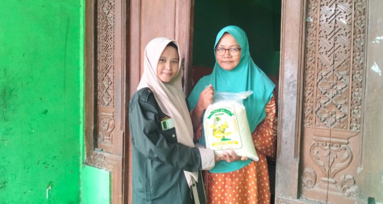 Winda, siswi SMK Muhammadiyah 2 Gresik, menyerahkan paket zakat fitrah kepada warga Desa Klampok dalam kegiatan penyaluran zakat oleh PR IPM SMK Muda Gresik. (Doc. Falaq)