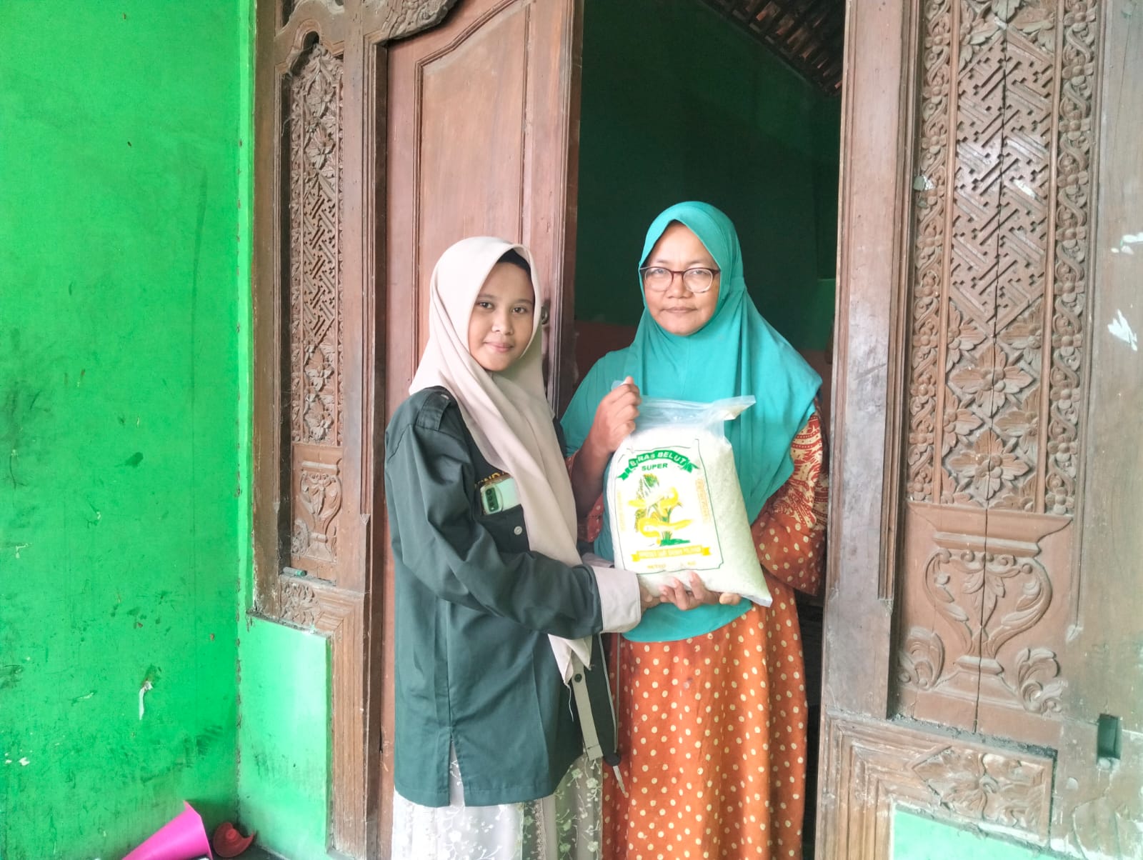 Winda, siswi SMK Muhammadiyah 2 Gresik, menyerahkan paket zakat fitrah kepada warga Desa Klampok dalam kegiatan penyaluran zakat oleh PR IPM SMK Muda Gresik. (Doc. Falaq)